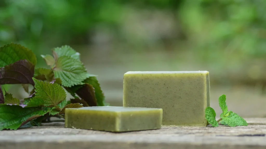 A stack of handmade natural soap bars with dried herbs and clay accents.