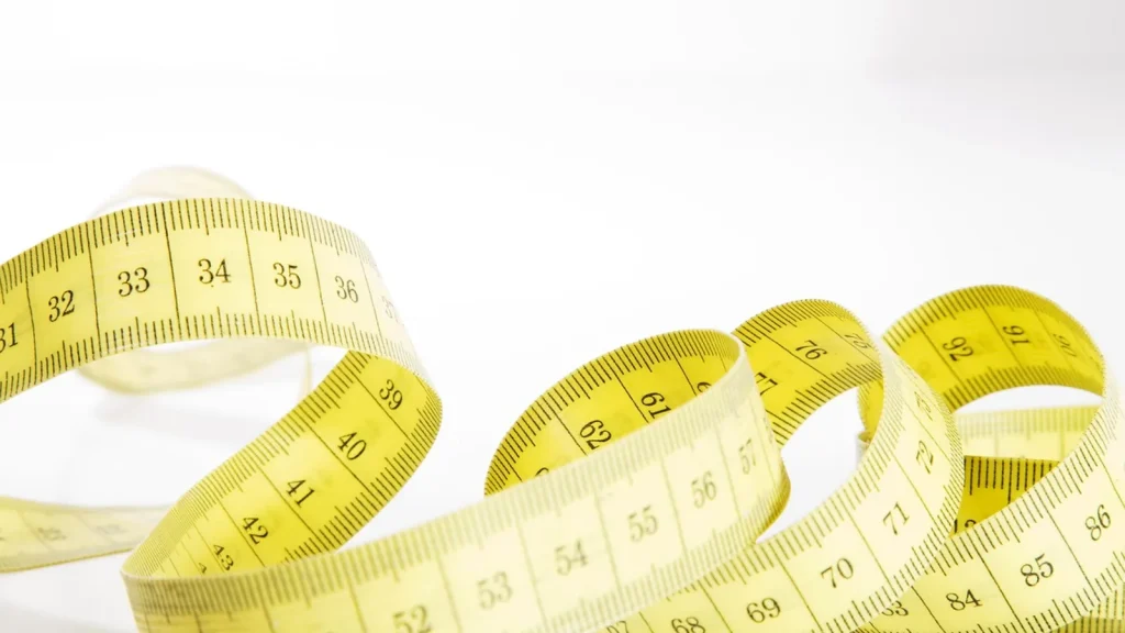 A woman measuring her underbust with a tape measure to find her bra size.