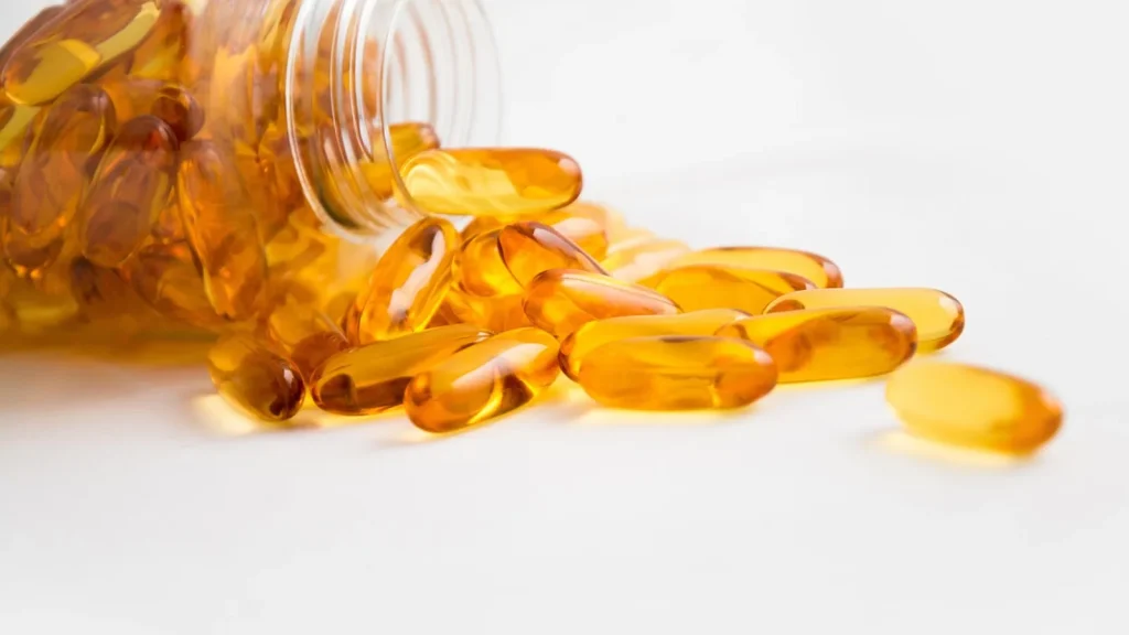 Small golden argan oil capsules next to a comb and a lock of shiny hair.