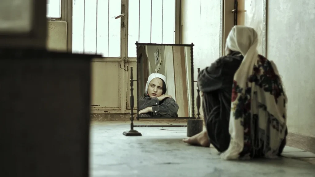 A woman smiling kindly at her reflection in a mirror.