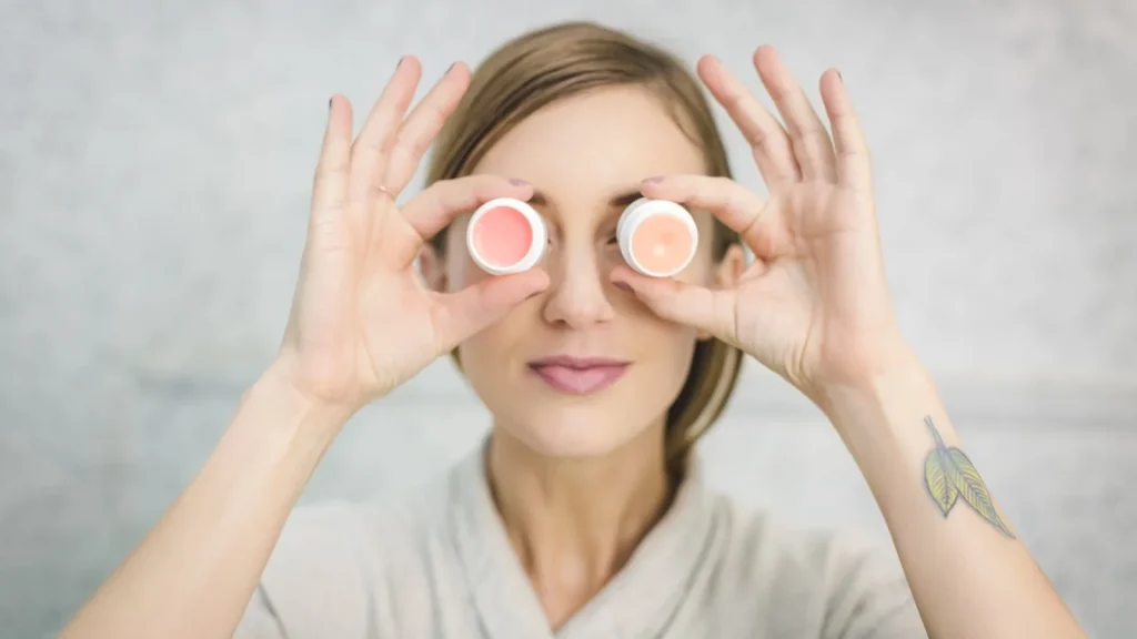 A woman applying SPF lip balm on a sunny beach.
