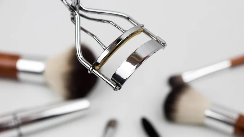 A woman applying eyelash serum along her lash line with a thin brush.