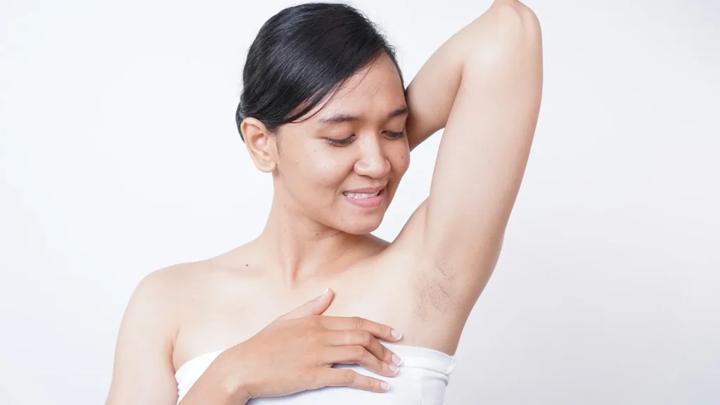 A woman applying a bronzing body lotion to wet skin in the shower.