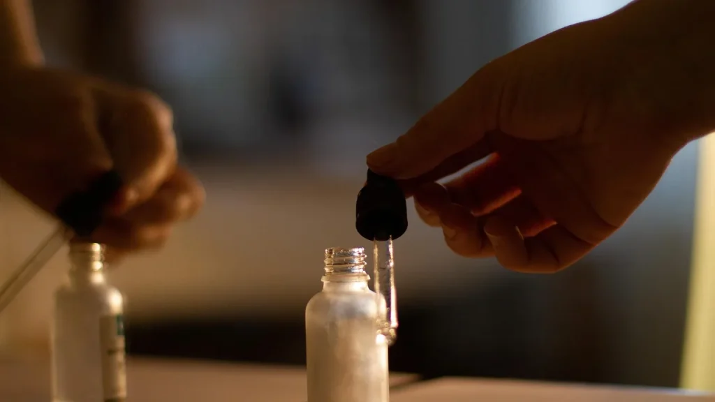 A glass dropper bottle of anti-wrinkle serum with a woman applying a drop to her face.