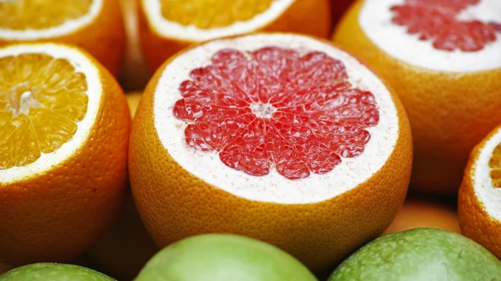 A vitamin C serum dropper bottle with orange slices, next to a woman applying it to her face.