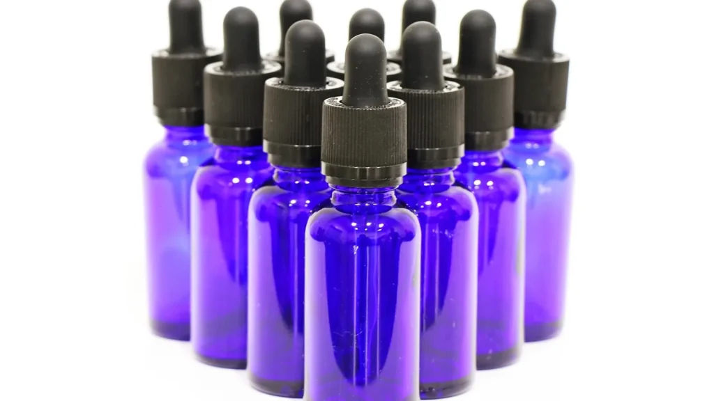 A glass serum dropper bottle with a face cream jar on a cozy autumn background.
