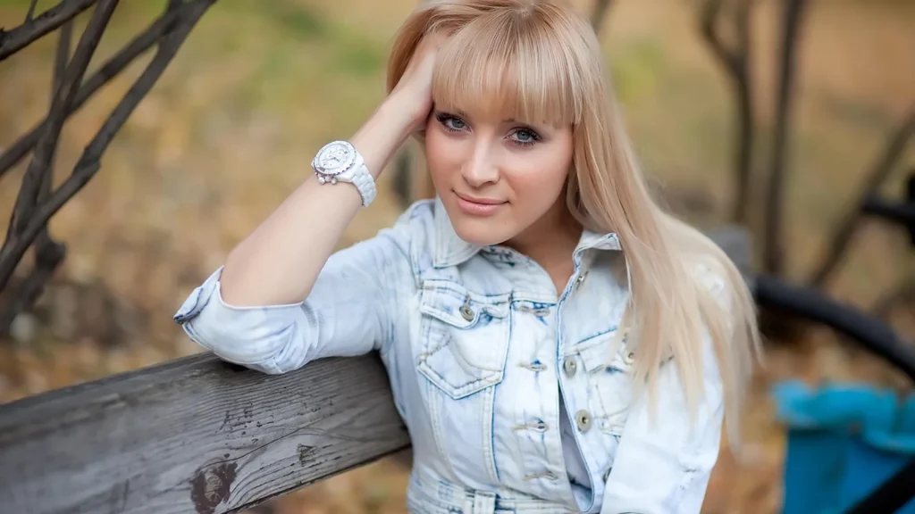 A woman with shiny long hair in an autumn park, scarf around her shoulders.