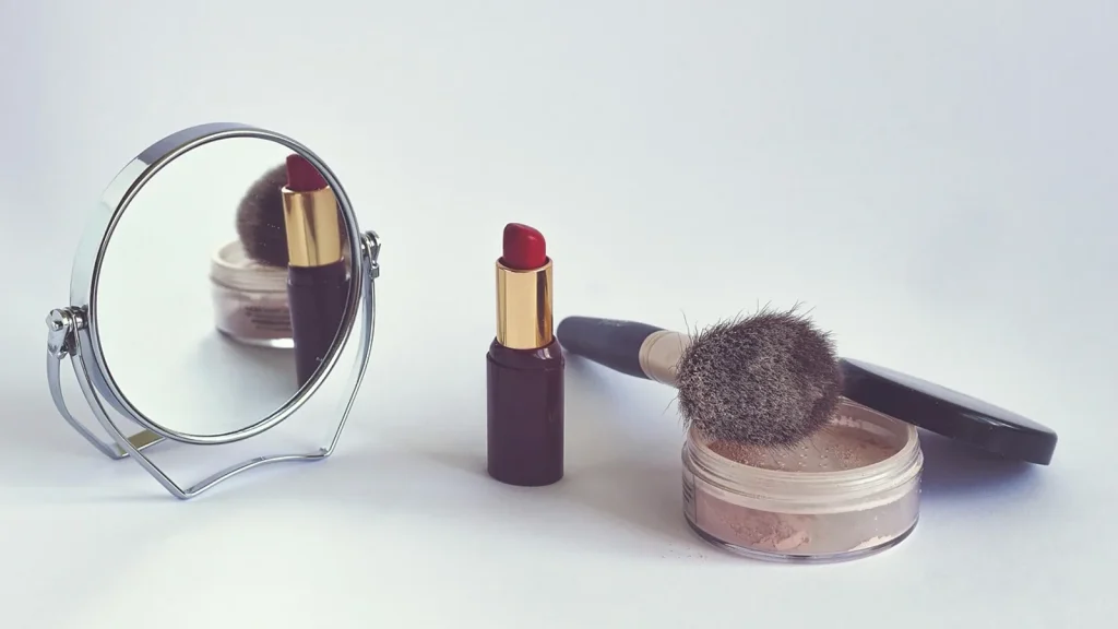 A large bamboo-handled powder brush dusting loose powder on a woman's face.