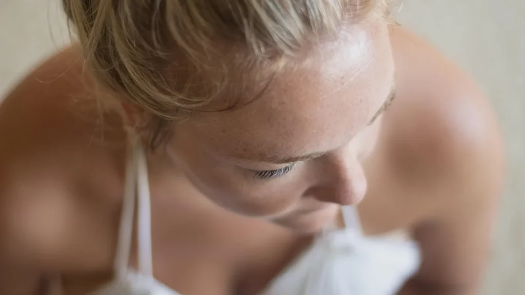 Fresh, radiant woman's face with a dewy glow on the cheekbones in soft daylight.