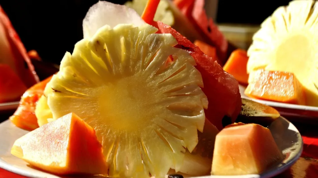 A face cleansing gel bottle surrounded by fresh papaya and pineapple slices.