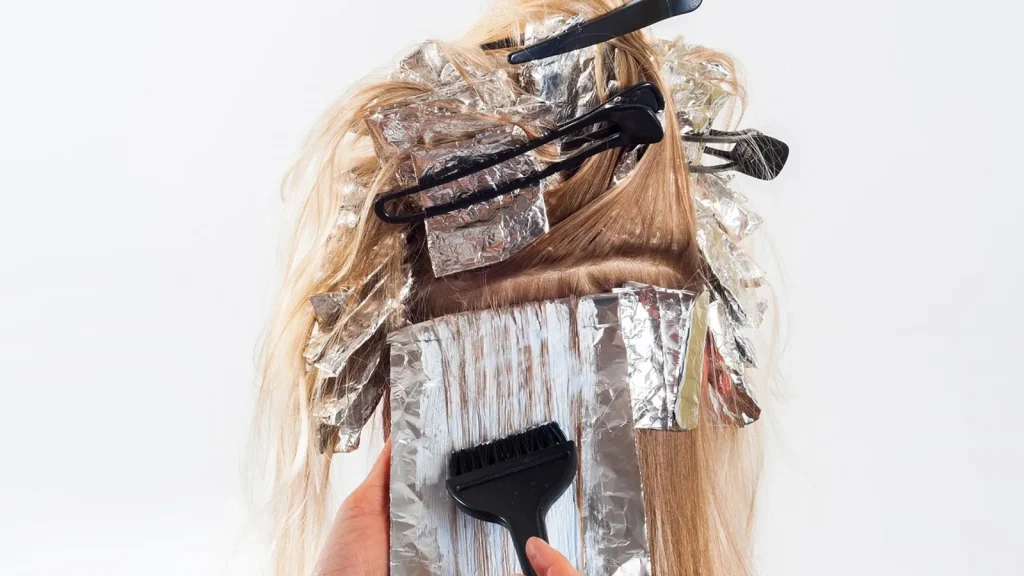 A woman applying conditioner to the lengths of her long wet hair.