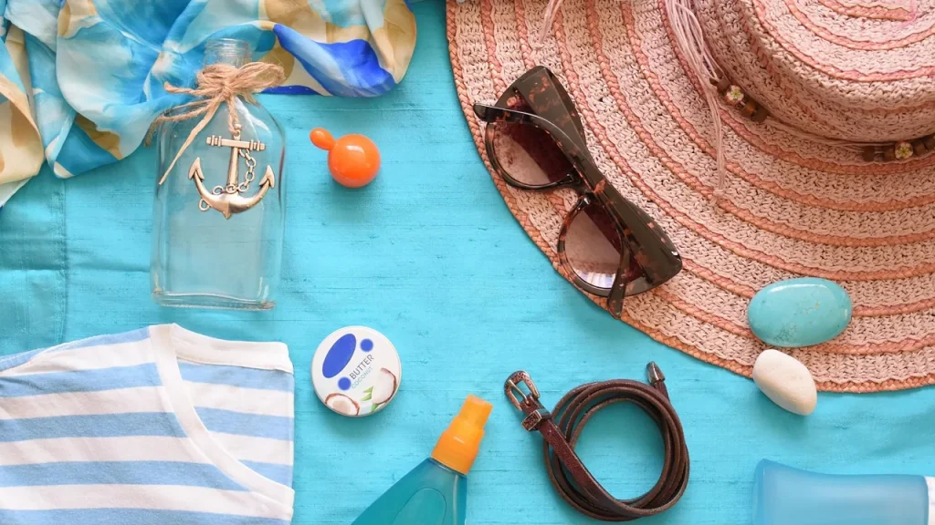 A cosmetic bag with sunscreen, after-sun lotion and travel-size toiletries laid out on a beach towel.