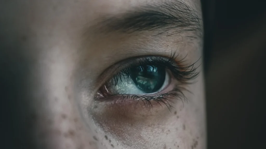 Close-up of a woman applying concealer or eye cream to the dark circles under her eyes.