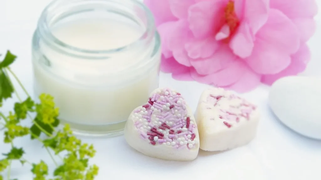 A jar of rich body butter next to raw shea butter and shea nuts.