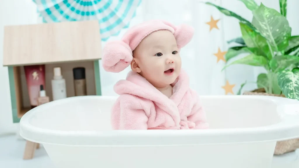 A parent gently applying emollient lotion to a baby after a warm bath.