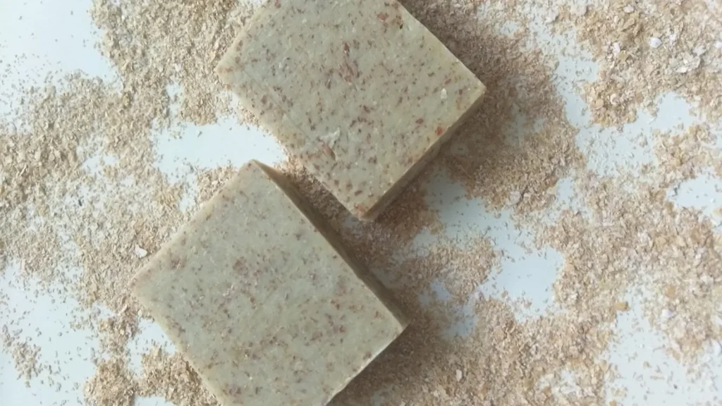 A jar of natural body scrub and body butter on a wooden surface with autumn leaves.