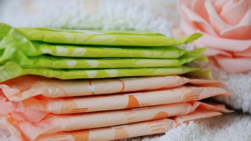 A menstrual cup, organic cotton pads and tampons arranged neatly on a pastel background.