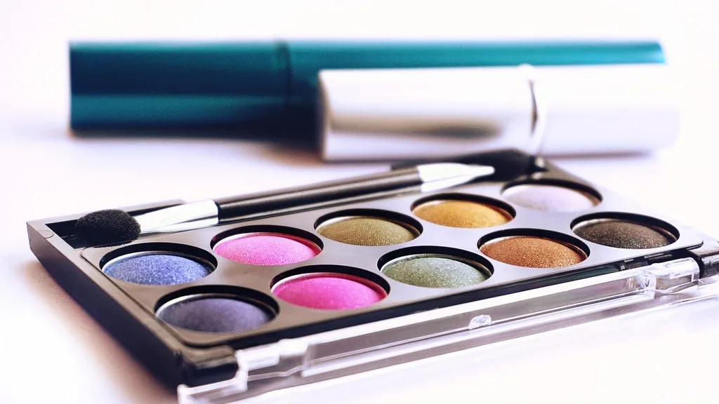 A colorful flat lay of lipsticks, eyeshadow palettes and makeup brushes.