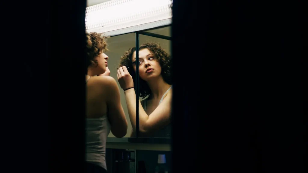 A woman examining expression lines on her forehead and around her eyes in a mirror.